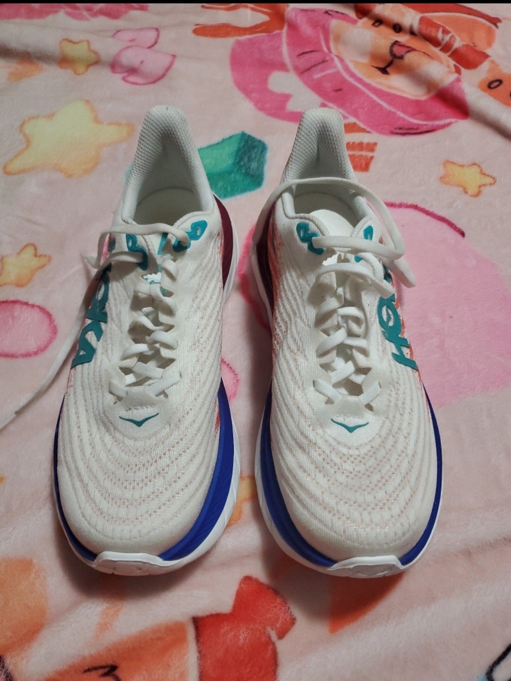 Hoka white running shoes with teal and blue accents